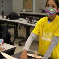 A camper works on her wooden airplane